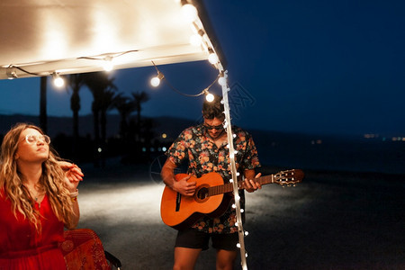 人们吉他自然派对男人晚上在一辆野营车旁边唱着朋友的歌图片