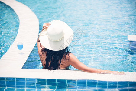 夏天女人穿比基尼和喝鸡尾酒在热暑假游泳池漂亮的吸引人图片