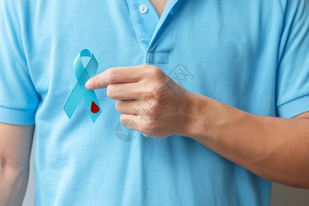 天诊断降低世界糖尿病日提高认识月1男子持有带血滴状的浅蓝丝带以支持人们生活预防和疾病保健前列腺癌症日概念人类携带轻蓝丝和血滴子以图片
