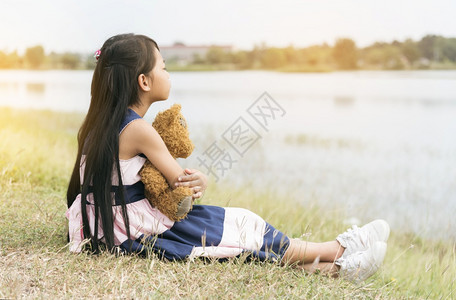 温暖的情感在绿公园操场的孩子们抱泰迪熊快乐为孩子最好的朋友Teddy为小可爱女孩做好朋友爱自闭症女孩快乐地玩团结图片