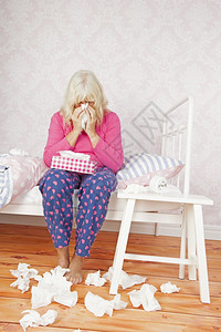 困扰躺在床上时用粉色睡衣和组织打鼻涕的悲伤女吹苦难图片