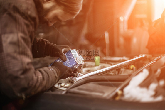 修理制动DOT4冷却器流体在一辆汽车里从时装的金属瓶子和日落颜色变化工人引擎图片