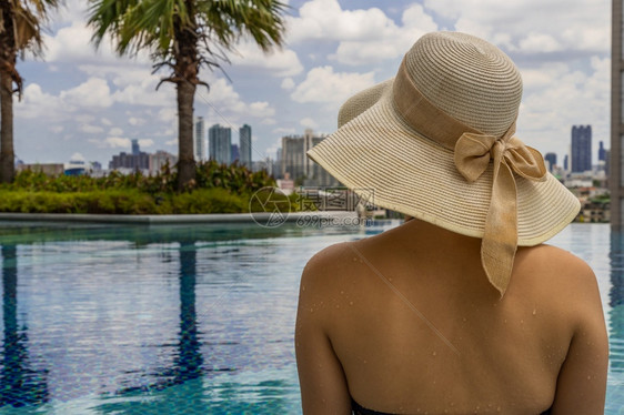 女孩奢华在阳光明媚的日间暑假概念中年轻女在游泳池放松帽子时的回视游客图片