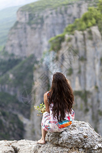 在峡谷抽烟的年轻女子地质学荒野攀登背景图片