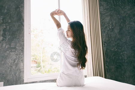 疲劳的在床上醒来亚裔女人完全休息早上打开窗帘呼吸新鲜空气得到亚洲人图片
