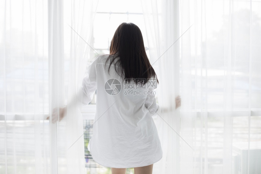 健康在床上醒来的亚裔女人完全休息早上打开窗帘呼吸新鲜空气拉紧早晨图片