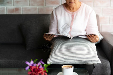 美丽的年老妇人在家里看一本带咖啡的书退休长老图片