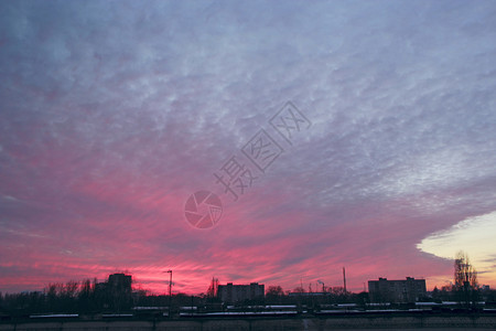 最佳红色日落在多层房屋之上夜晚城市景色风黄昏在紫光镇的暮市风云夜城红夕阳上大粉色乌云在晚城边的大粉色乌云生活天空图片