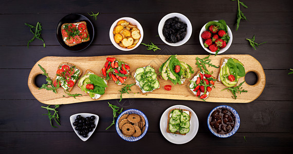 平整的健康素食晚餐桌配有番茄黄瓜鳄梨草莓药和橄榄零食收藏最佳牛油果图片