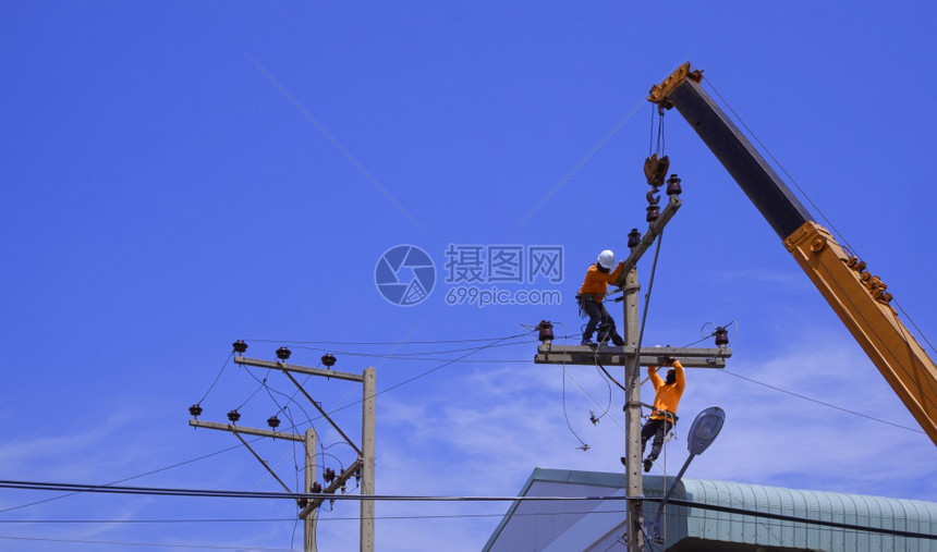 电气城市的两名配备起重车的电工正在蓝色天空背景下安装电线杆上的机设备并安装起重卡车力量图片