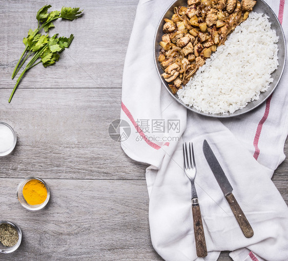 炸玉米饼番茄用洋葱和米饭开胃火鸡将洋葱和大米撒在半锅上放白餐巾纸上用刀子和叉香料草药铺在灰色的生锈木本底顶端热的图片