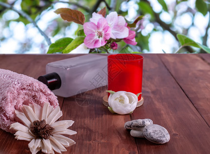 编织放松女化红蜡烛白花棕榈石和红蜡烛在盛开花朵背景下的粉色毛巾香水概念石头油和红蜡烛图片