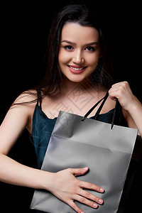 买快乐身着深绿裙子的年轻美女手里拿着黑纸购物袋在色孤立的背景下被困在她手上年轻的图片