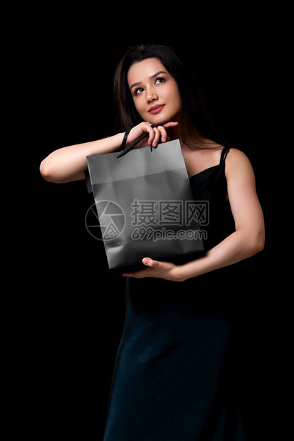 购买身着深绿裙子的年轻美女手里拿着黑纸购物袋在色孤立的背景下被困在她手上零售购物者图片