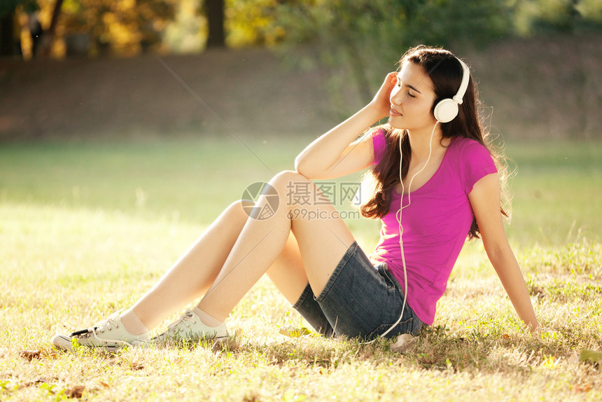 草地上听音乐的年轻女人图片