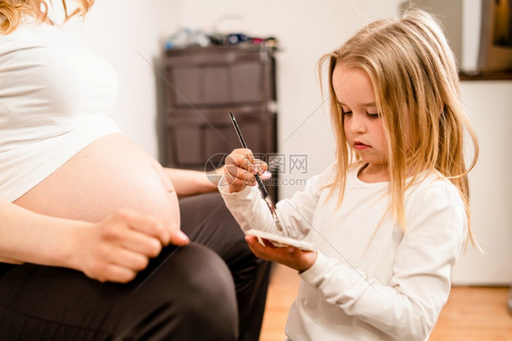 小女孩在母亲孕肚上画画图片