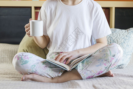 内部的年轻金发美女坐在床上喝着一杯咖啡穿睡衣的咖啡在家庭气氛中黑发金的图片