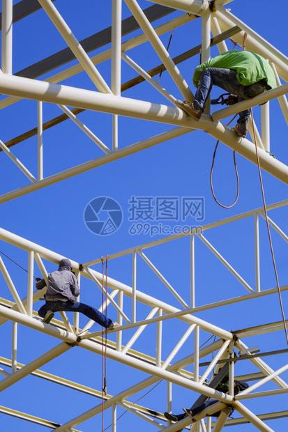 亚洲建筑工人群体在屋顶建筑结构上焊接金属垂直框架蓝天空背景下对色天空背景的亚洲建筑工人纵角电缆高的工具图片