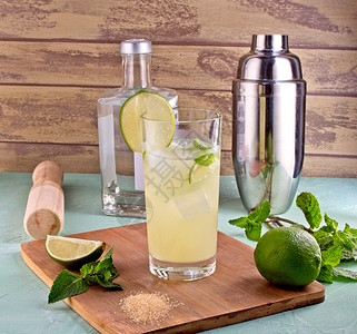 绿色木制的莫吉托鸡尾酒装饰包括石灰薄荷叶冰块和银摇晃器Shaker柠檬石灰薄荷叶和夏季鸡尾酒的冰补品图片
