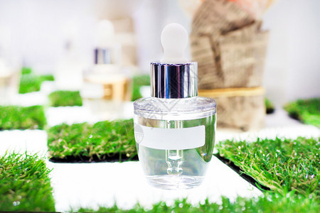 白色清玻璃瓶和管子贴上标签紧绿草背景浅滴管吸化妆品图片