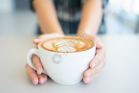 喝女人手拿着白咖啡杯是木桌上的一张拿铁咖啡桌复古风格从顶部看到奶泡的沫液体黑色图片