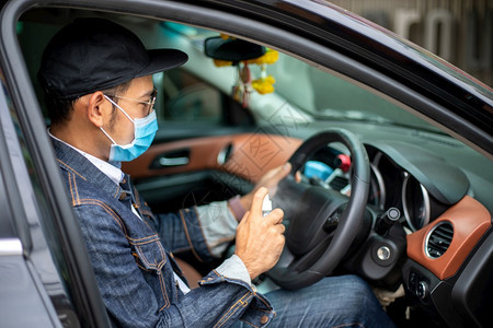 亚洲男子使用喷洒酒精清洁汽车以保护冠状的亚洲男子新冠消毒剂大流行图片