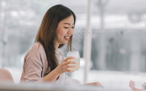 新鲜亚洲美丽的年轻女在微笑家休息时喝着果汁享受生活方式概念自在食物图片