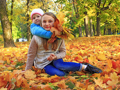 秋天落叶里玩耍的姐姐和妹妹图片