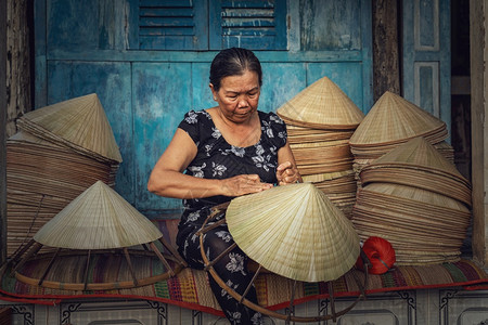 覆盖声望很高的在越南霍希明市ApThoiPhuoc村的老旧传统房屋中越南老工匠在传统艺术家概念中制作传统维特南帽村民图片