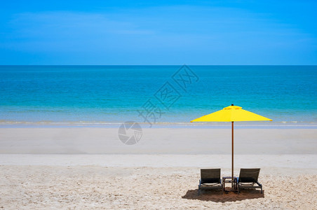 海滩天夏热带季沙滩在阳光明媚的日间长途旅行和暑假概念下用黄色雨伞蓝海背景和配有两张坐椅图片