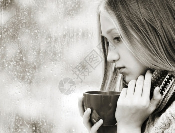 金发女郎美丽孩的情感肖像长金发头杯茶望着远方在雨月秋日喝茶情绪化的悲伤图片