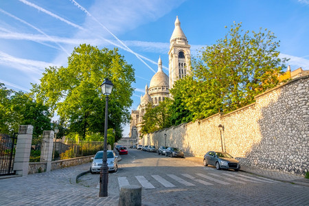 城市的天空地标在巴黎的夏日阳光明媚巴黎圣柯尔修道院屋顶对着蓝天数辆汽车停在科布石街上圣库尔修道院和有公车的科布斯通街图片