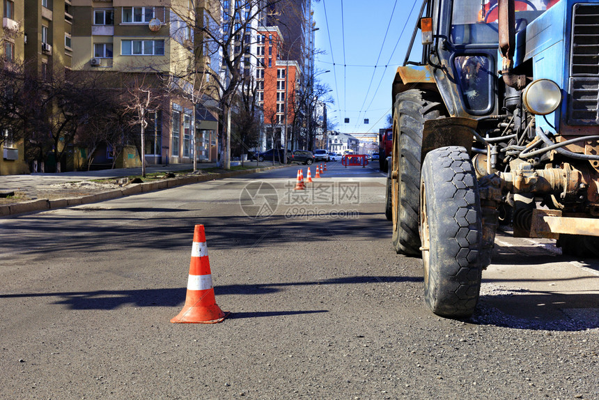 振动器道路施工橙色交通锥体和一辆旧拖拉机在城市街道上有一个修路区Orange交通锥体沿城市街道边缘有一个维修区天空图片