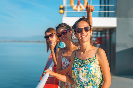 船上渡轮的甲板三名年轻女在阳光明媚的假日朋友们欢笑时对目的地或天空指向目的地或天空美丽女孩们喜悦图片