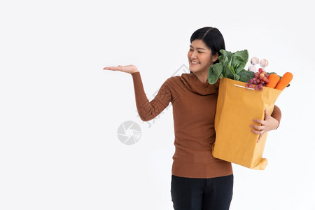 美丽的市场棕榈快乐亚洲妇女微笑打开手掌在从杂货店来的送信人到家里货后带着一个购物袋为种新的生活方式而提供超市交货概念图片