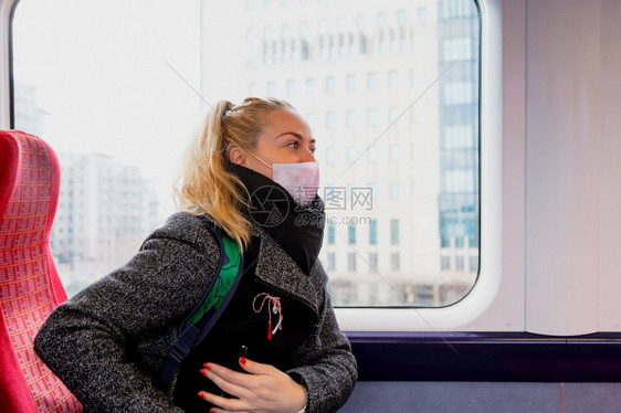 由于冠状有卫生面罩的妇女可以在火车座椅上保持安全距离因为冠状面部的新冠禁止图片