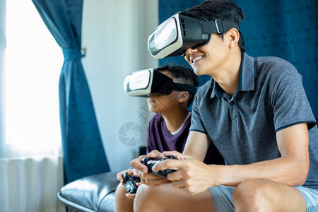 亚洲人父亲和儿子在家中客厅享受游戏与视频玩棍和虚拟现实眼镜一起玩游戏令人振奋非常有趣的娱乐技术激动图片