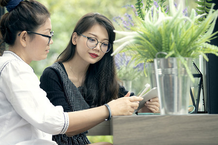 兄弟吸引人的两个手拿着智能机的亚洲女人在客厅里说话面带快乐的脸庞年轻图片