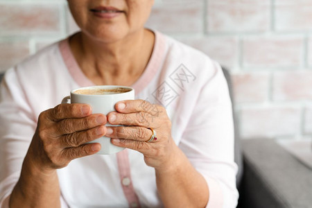 老太婆在家喝杯热咖啡回家喝微笑老年活的图片