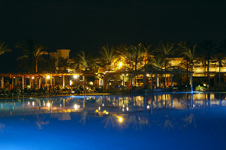 屋派对度假的游泳池和晚间酒店人们上在游泳池附近放松晚间酒店的灯光在夜晚游泳池水中反射热带图片