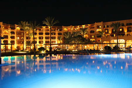 假期度的游泳池和晚间酒店人们上在游泳池附近放松晚间酒店的灯光在夜晚游泳池水中反射屋美丽的图片