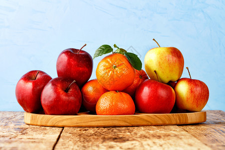 丰富多彩的一种农场红熟苹果和绿叶橘子放在浅蓝色背景的旧木桌上托盘复制空间红熟苹果和绿叶橘子放在浅蓝色背景旧木桌上的托盘图片
