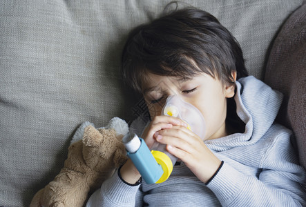 健康医疗的药物患有哮喘过敏症的TriedKid使用哮喘吸入器进行过敏他因咳胸部嗽而疲倦并持有吸入器口服图片