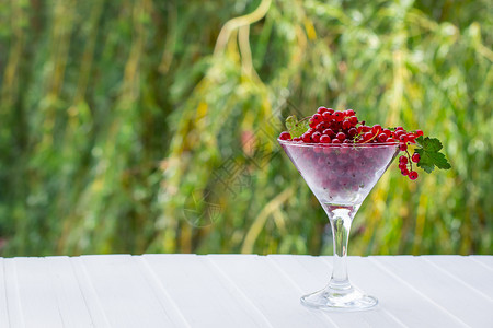 素食主义者在厨房木桌板上的玻璃瓶子新鲜红花杯装在玻璃子上甜点果汁酱准备保护草莓鲜红花的夏天收获生白色图片