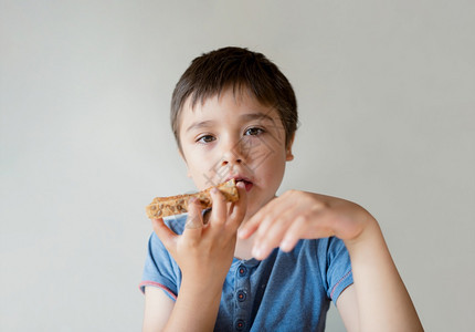 年轻的蜜糖可爱儿童男孩在上学前吃早餐时用烤成的蜂蜜乐孩子早上在面包吃黄油为儿童提供健康食物的概念a健康食品图片