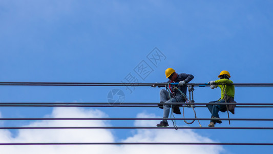 电工安全系统地在高压下安全装电缆的动工程并有系统地在天空和蓝上安装高压电缆超过技术员图片