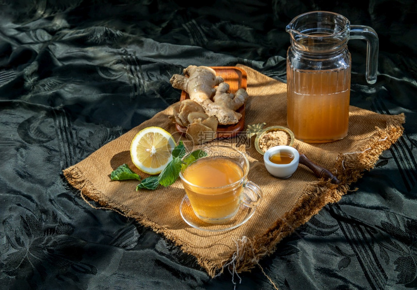 切片绿色草本植物热姜汁加柠檬和薄荷根小片姜汁含红糖和蜂蜜盛满棕色糖和麻布的蜂蜜热姜汁可以帮助身体变暖健康饮用图片