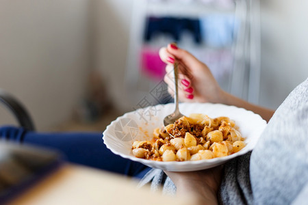 成人在盘子上的侧视图面食和肉酱未知的女天主教拿着食物在大腿上勺子另一只手里白天吃东西人们欧洲的图片