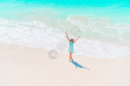 海滨旅行滩上美丽的女孩在浅水海滩上从面看浅水快乐女孩在海滩玩得很开心在浅水女士图片
