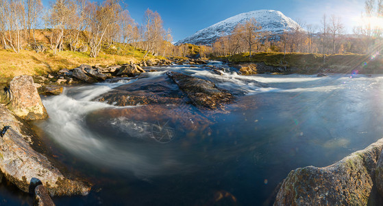 木头瀑布挪威阳光明媚的秋天蓝水金树雪覆盖的山丘蓝色水金树和雪覆盖的山峰河图片